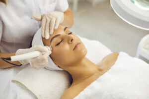 Close up of a smiling woman receiving microdermabrasion from her esthetician for smoother skin.
