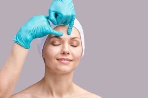Happy middle aged woman having her brow examined by a plastic surgeon before her brow lift.