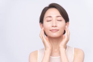 Young woman touching her smooth, shiny skin after getting a facial exfoliation treatment.