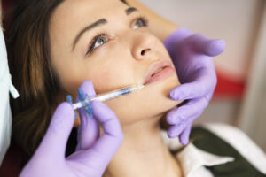 Woman receiving lip filler injections for fuller, more even lips.