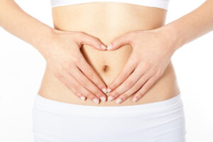 Close up of a woman with her hands pressed to her flat stomach after getting body contouring surgery.