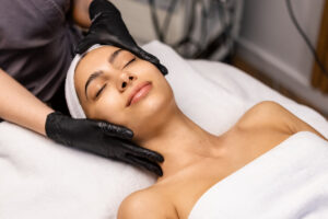 Woman happily receiving a Glo2Facial at the spa for smoother, healthier, and more radiant skin.