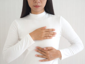 Close-up of a woman with her hands around her breast to show that she's considering a breast implant replacement.