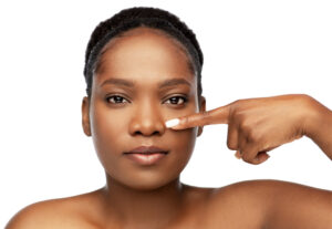 Young beautiful, black woman pointing at her nose, considering a rhinoplasty for improved look or function.