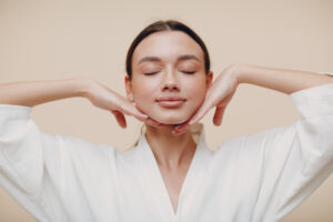 Beautiful woman with her face in her hands, emphasizing her jawline after a facelift.